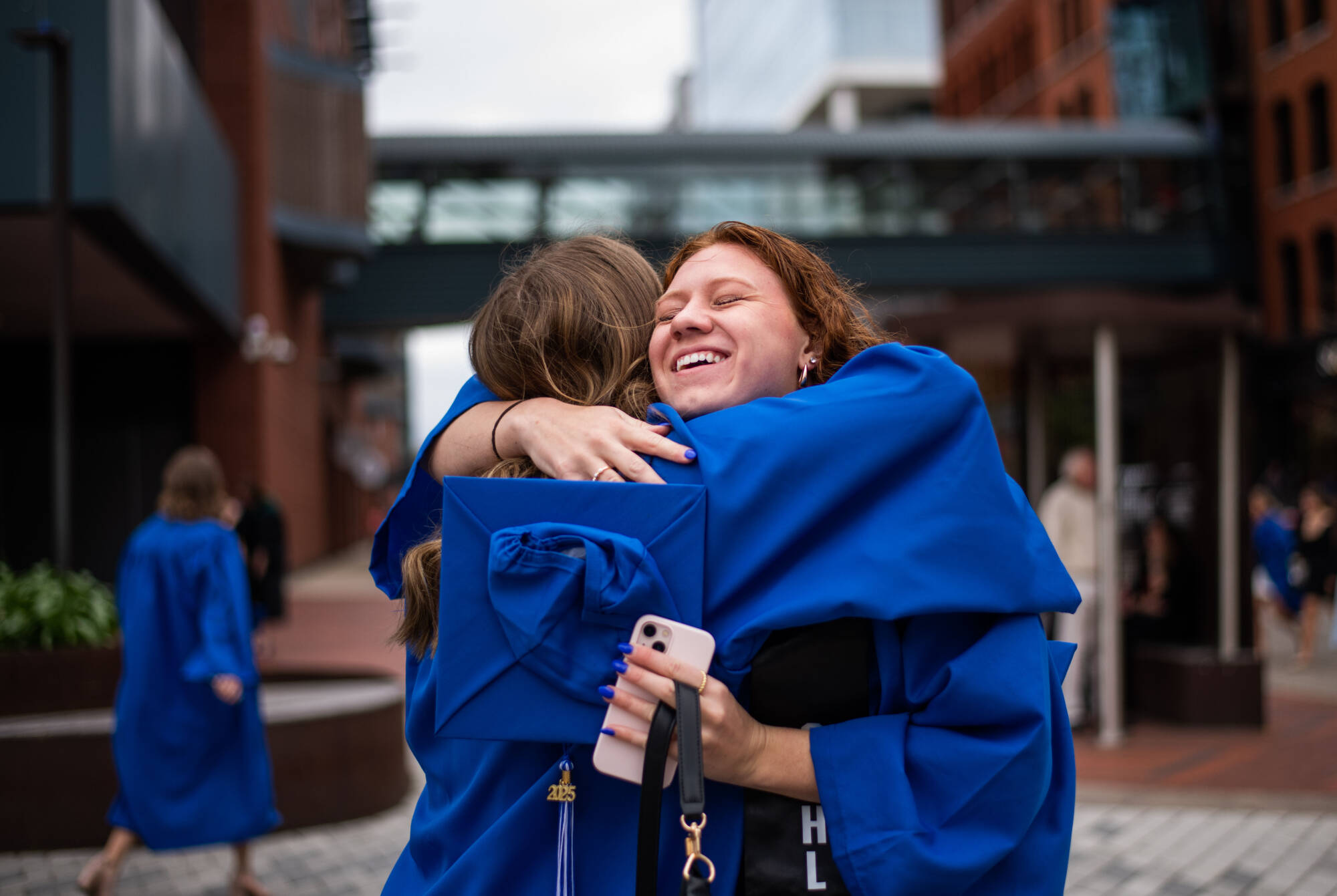 Recreational therapy graduate Sydney Affholder, left, is hugged by marketing and finance graduate, Kayley Gallagher, before the start of the Saturday morning Commencement April 26.
